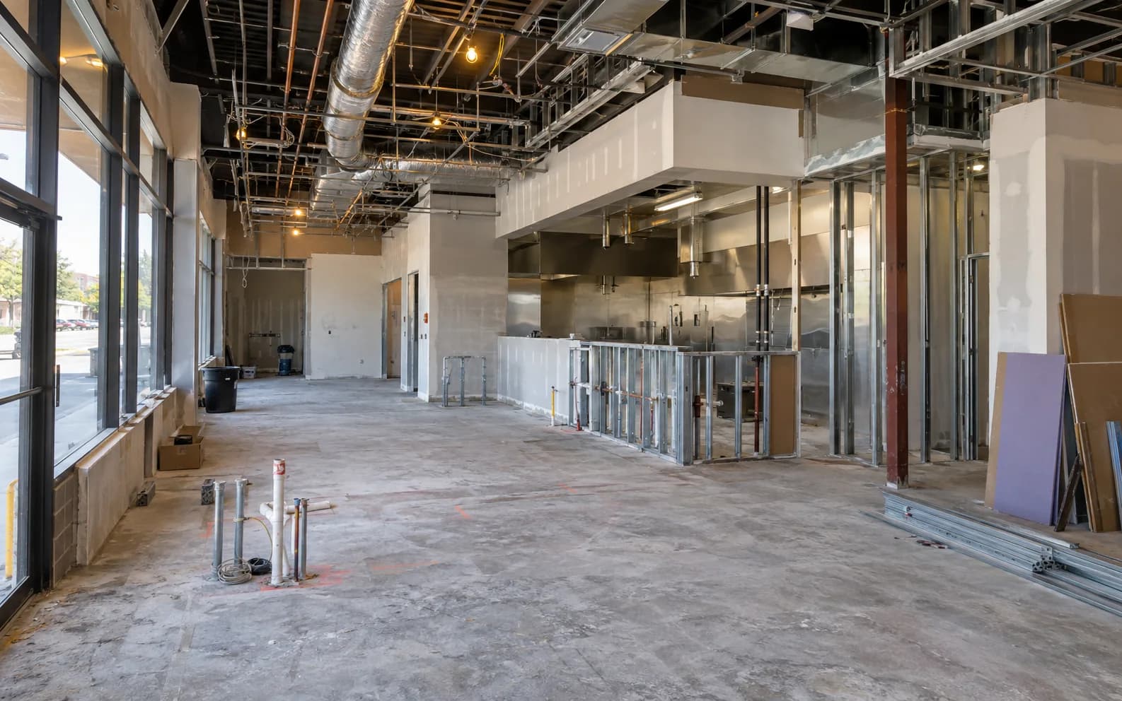 Restaurant interior during renovation with open ceiling, kitchen rough-in and unfinished service area