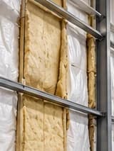 Exposed insulation with damaged facing at a metal warehouse wall